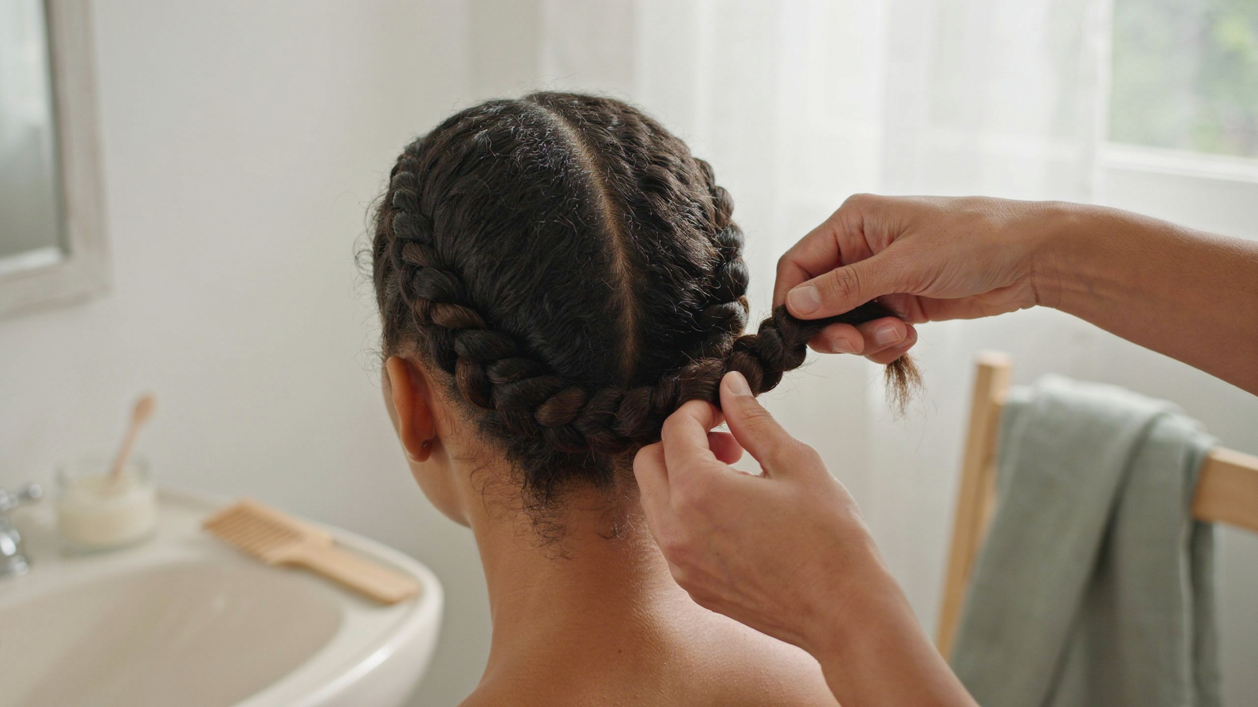 Mains ajoutant progressivement des mèches à une tresse africaine