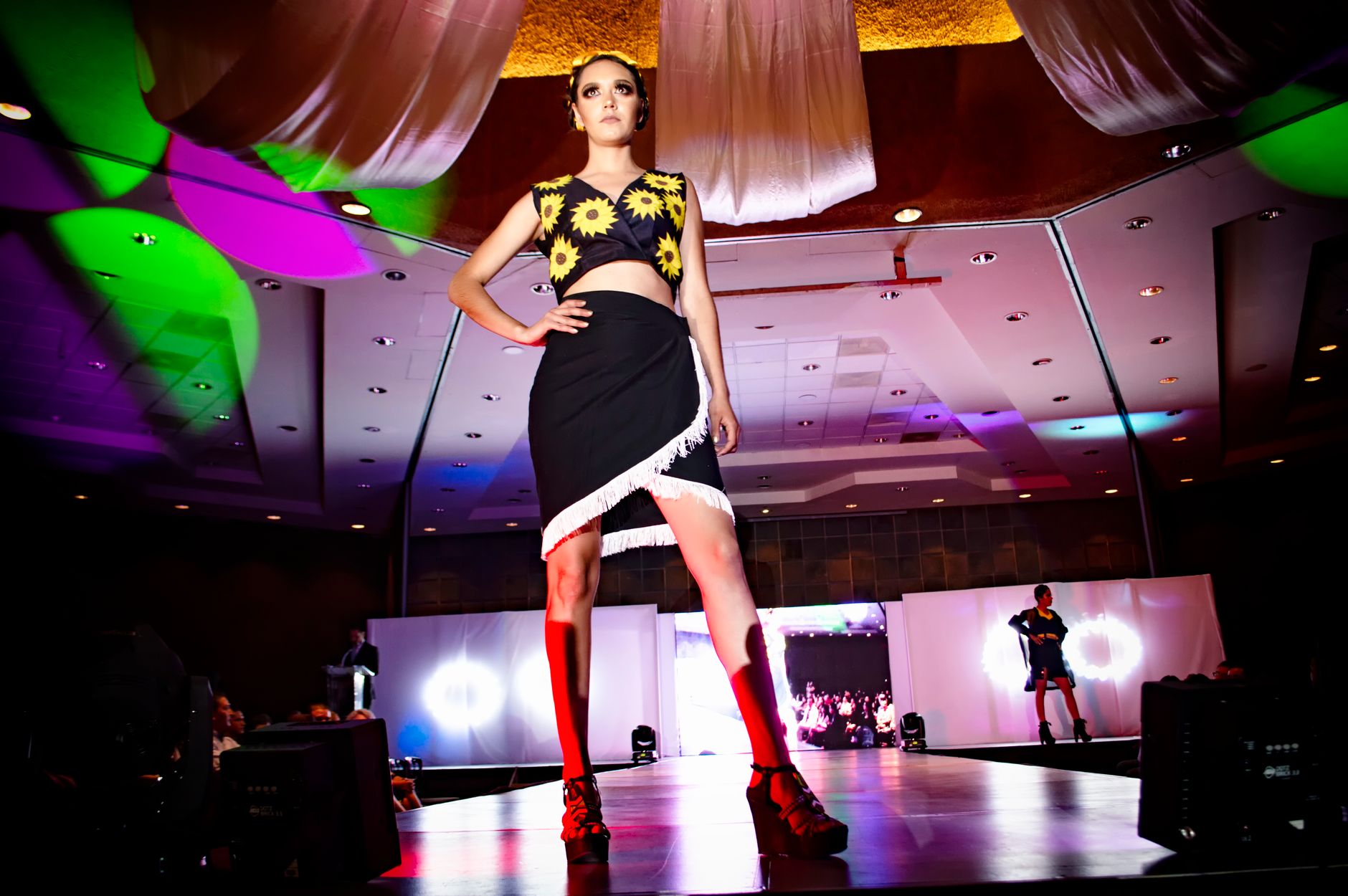 Dynamic fashion model on stage at a vibrant Morelia fashion show.
