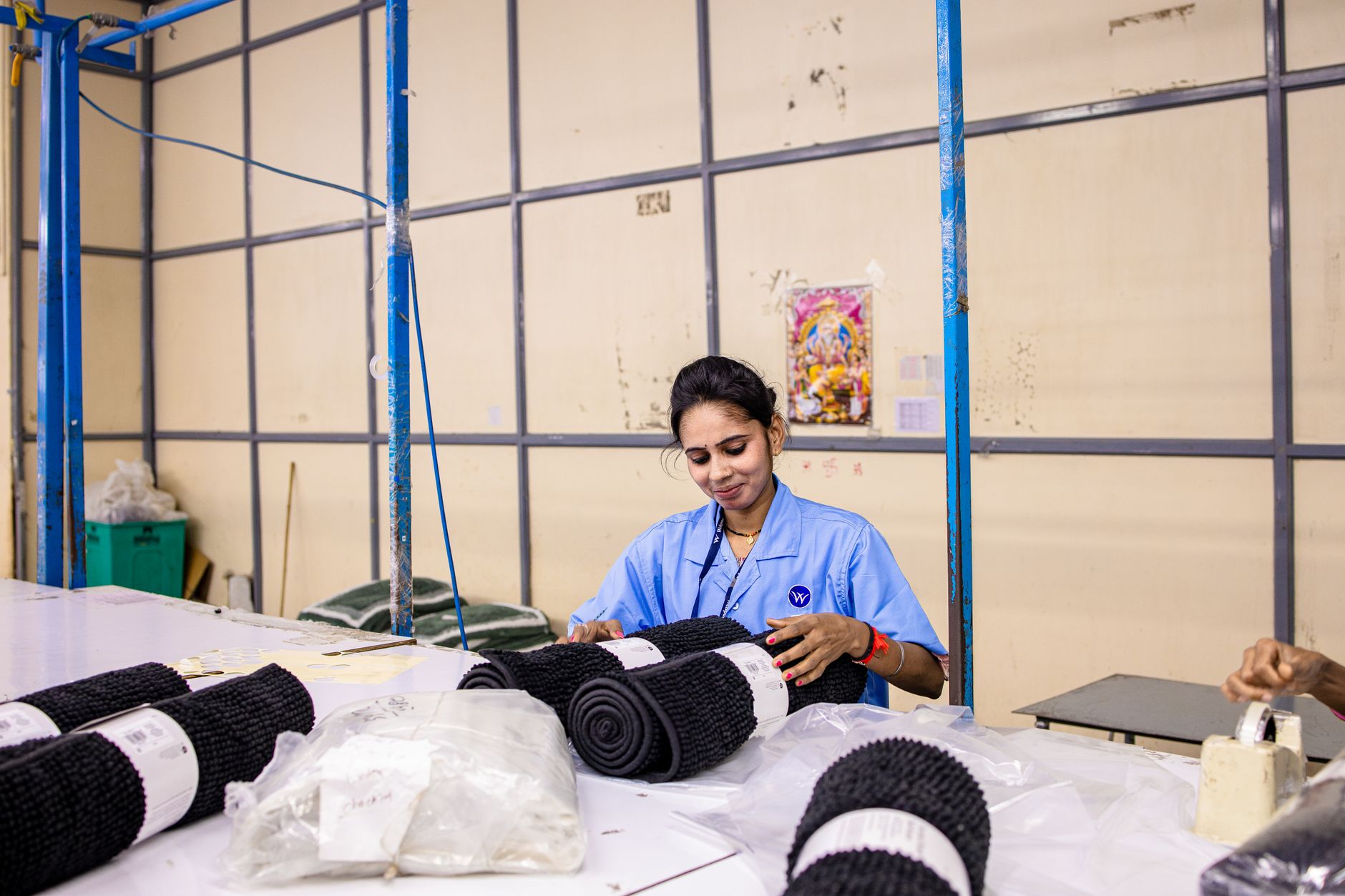 Female worker organizing textiles in a factory environment, showcasing blue-collar labor.