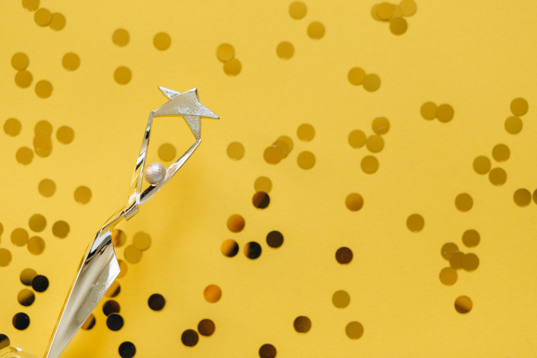 Un trophée en argent avec un design d'étoile sur un fond jaune vif orné de confettis.