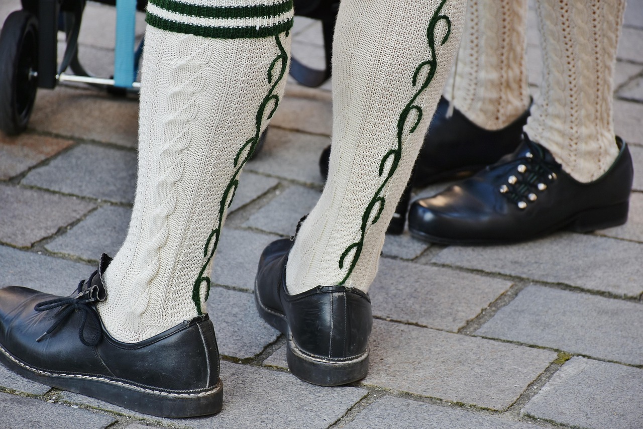 Chaussettes hautes en maille torsadée écrue portées avec des souliers en cuir noir sur des pavés.